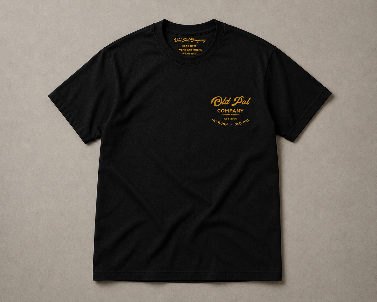 Black heavyweight Cotton T-Shirt with mustard Old Pal Company chest print laid flat on neutral background